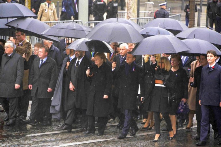 當地時間11月11日，紀念一戰結束100周年官方儀式在巴黎凱旋門隆重舉行。圖為法國總統馬克龍、德國總理默克爾、加拿大總理特魯多、歐盟委員會主席容克等政要在雨中共同走向凱旋門的儀式現場。     (中新社)