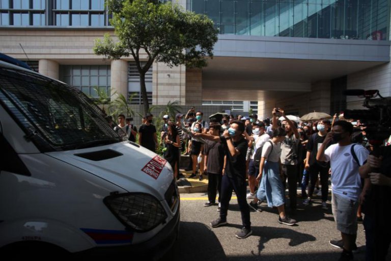 大批人聚集在西九龍裁判法院外，包圍警車，指罵車上警員。