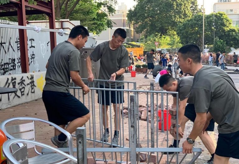 解放軍駐港部隊成員在九龍塘軍營外協助坊眾清理路障。