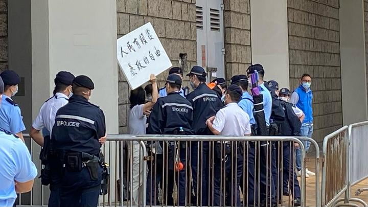 法院外有人高舉標語示威，警員上前制止。

