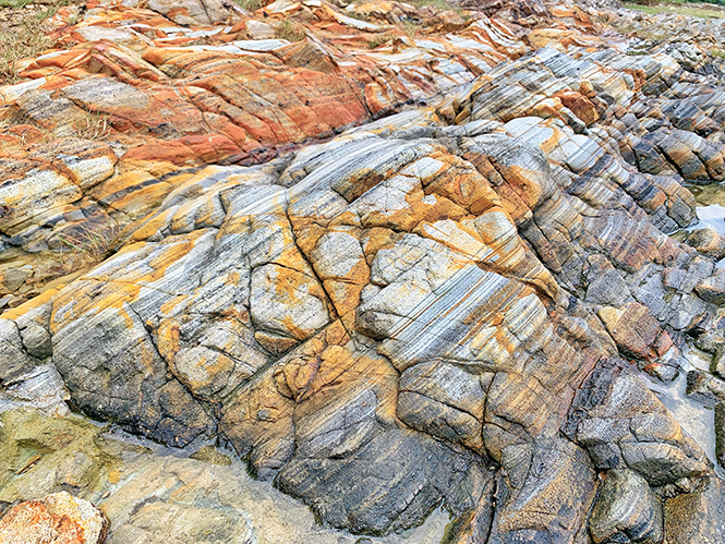 岩石一層層色彩相間，如沙瓶紋理般，是香港較罕見的沉凝灰岩。