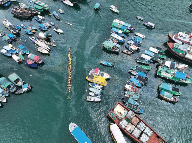 一艘龍舟穿梭於停泊滿漁船的香港仔避風塘。