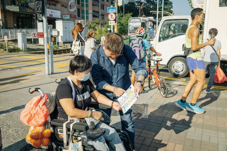 鄧德成（右）向經過的市民介紹參選政綱，坐著輪椅的街坊杜小姐（左）表示，希望他當選後可以改善區內交通問題。
