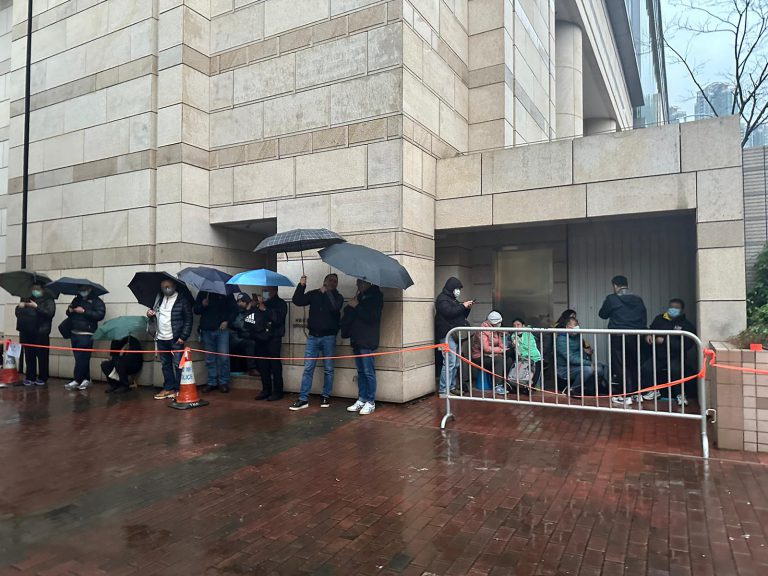 排隊的市民撐傘式躲到建築物內避雨。（張雨娜攝）